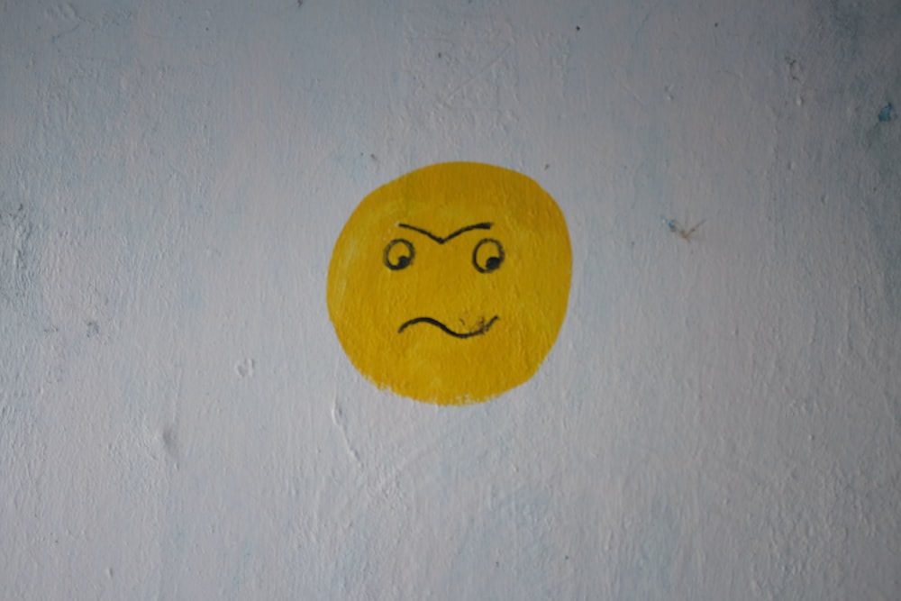 a yellow smiley face painted on a white wall