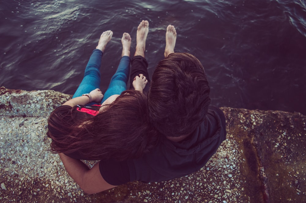 person in black top sitting in front of body of water