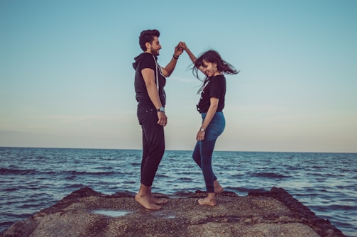 A cinematic shot of a couple dancing barefoot on a beach during their pre-wedding shoot.