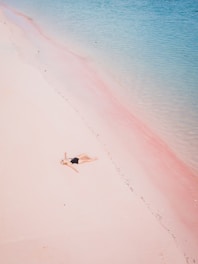 a woman laying on a beach next to a body of water