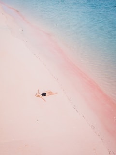 a woman laying on a beach next to a body of water