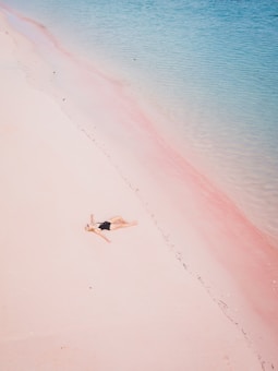a woman laying on a beach next to a body of water