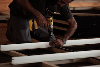 A skilled construction worker confidently using a Fortiva power drill on a building site.