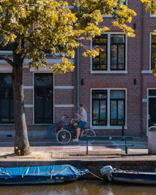 A happy rider using the Veloza app while waiting beside their bike in a bustling urban park.