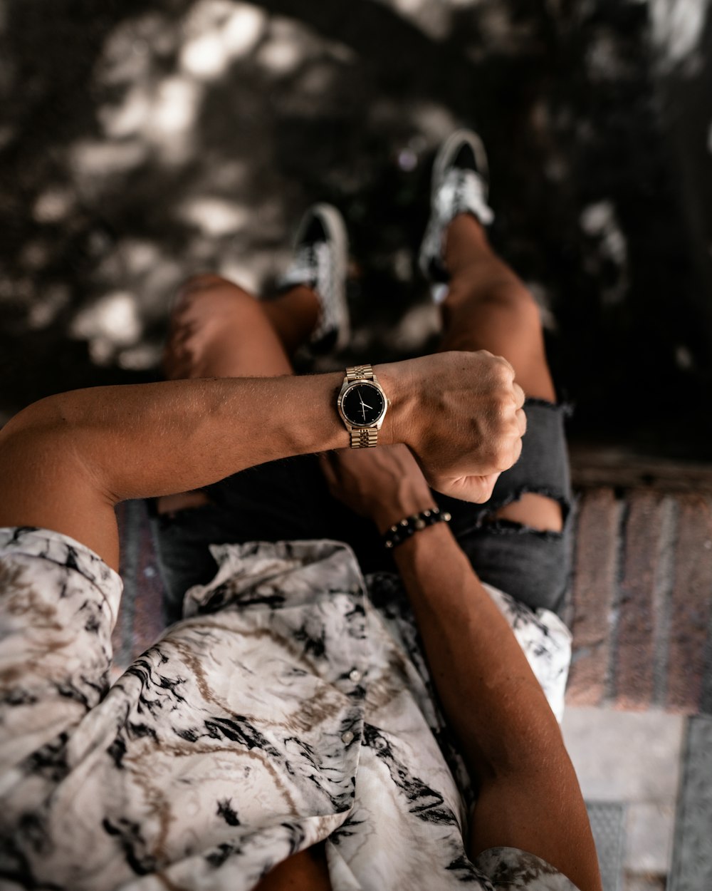 selective focus photography of sitting man showing analog watch
