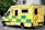 A large, yellow and green emergency ambulance is parked on a city street. The vehicle is part of the London Ambulance Service, as indicated by the text and logos on its side. It features red and yellow chevron patterns on the back doors and displays several identification numbers and emergency contact information.