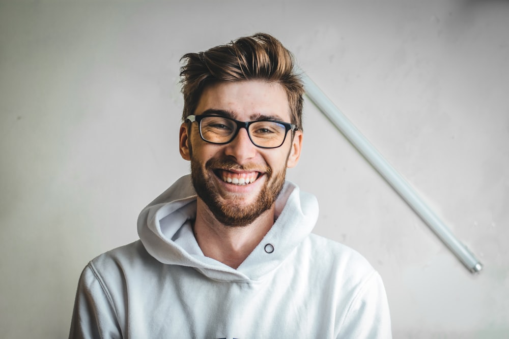 smiling man wearing black framed eyeglasses and white hoodie