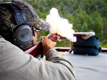 Instructor demonstrating shooting techniques at an outdoor shooting range.
