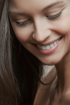 Soft-lit photo showing a client smiling gently, highlighting subtle, natural eyelash extensions.