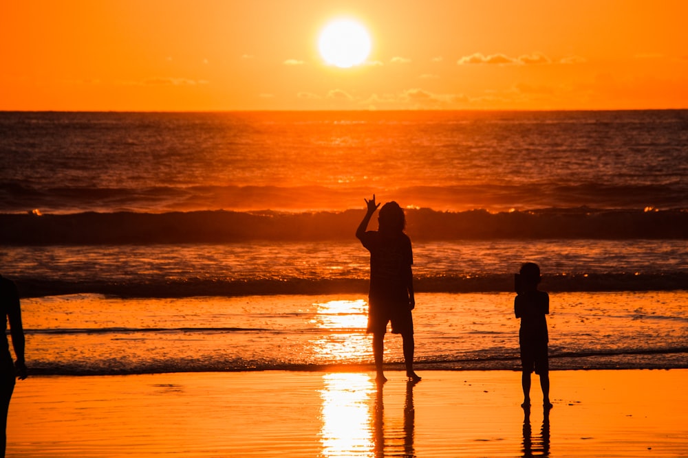 silhouette photography of toddler standing near body of water