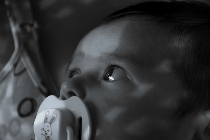 Close-up of a smooth, honey-colored natural latex pacifier with soft texture