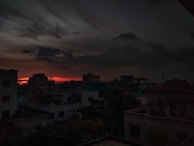 A cinematic shot of a cityscape at dusk with glowing red and black tones.