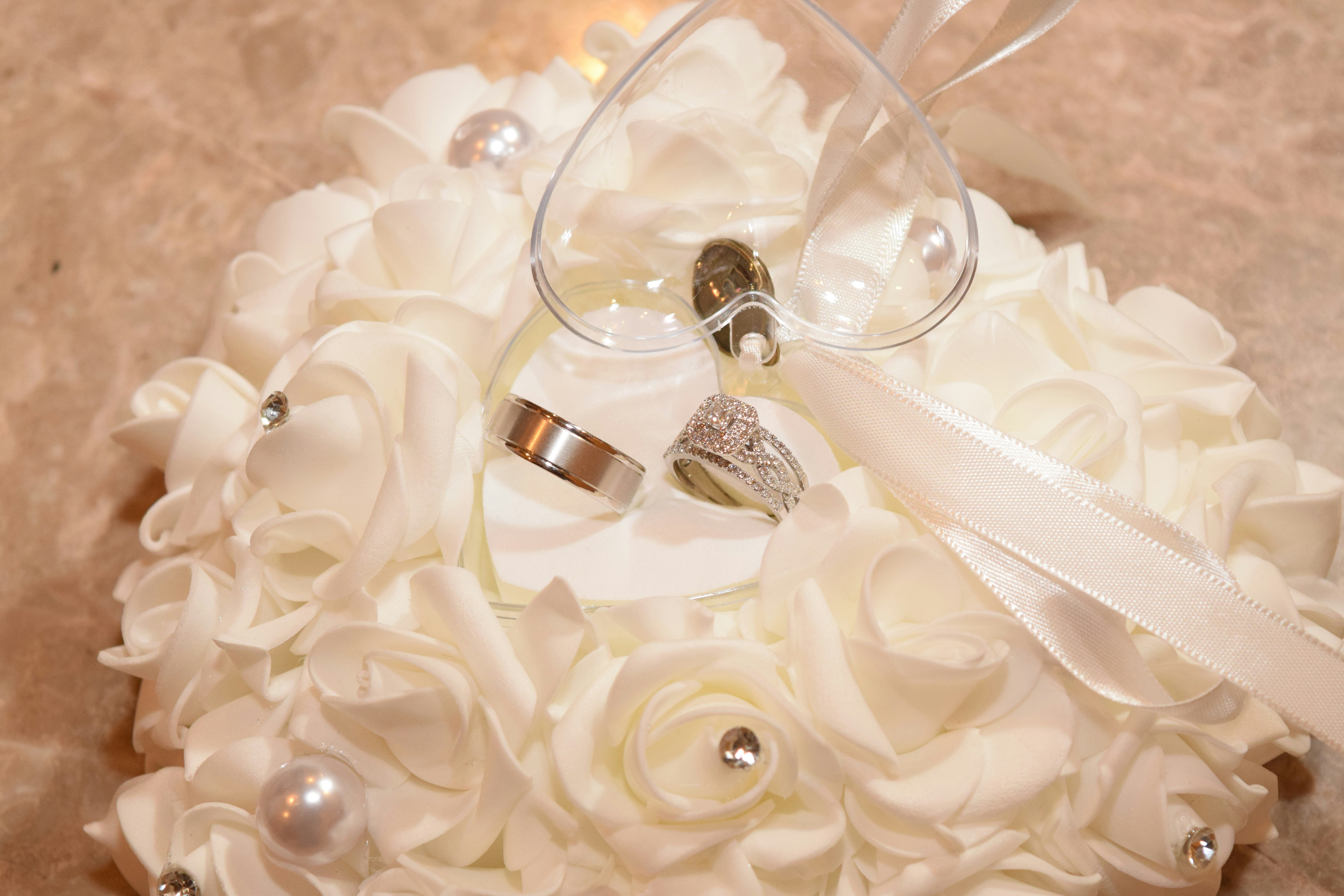 Détail de bague de fiançailles dorée sur fond de pétales de roses blanches