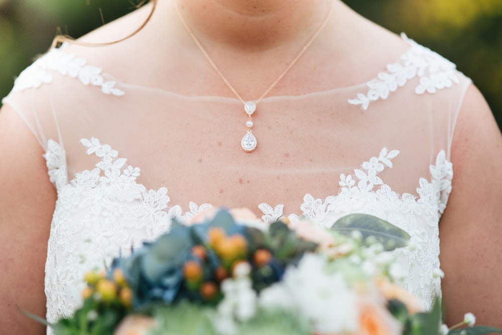 Fotografia di messa a fuoco selettiva della donna che indossa il vestito da sposa che tiene il bouquet