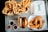 An overhead view of a tray filled with fast food items, including two boxes of golden fries, a cheeseburger in a wrapper, crispy chicken tenders in a box, and small containers of dipping sauces. The words 'Roost' are visible on one of the takeout boxes.