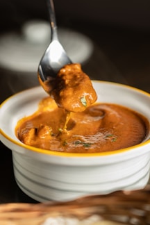 Close-up of creamy golden desi ghee in a traditional clay pot with a wooden spoon.