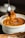 A close-up of a smiling customer enjoying a vibrant Indian curry dish at a restaurant table.