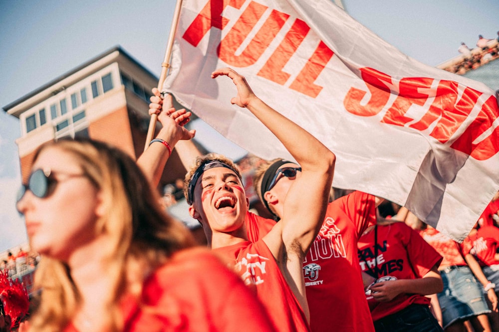 people wearing a red shirt holding banner during daytime