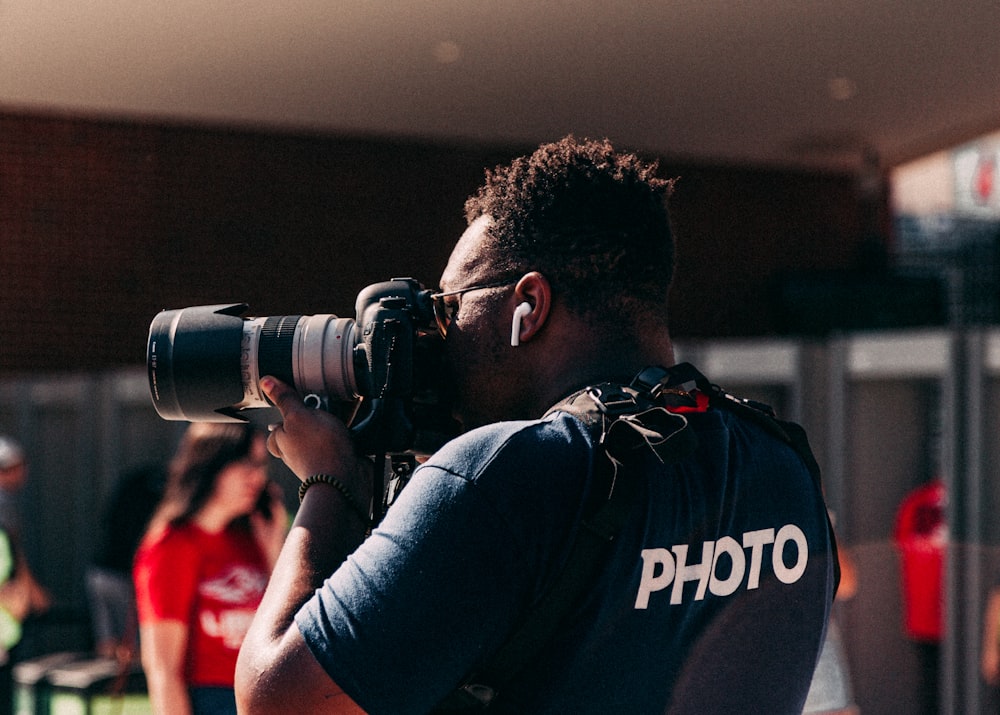 man wearing black shirt taking photo using DSLR camera