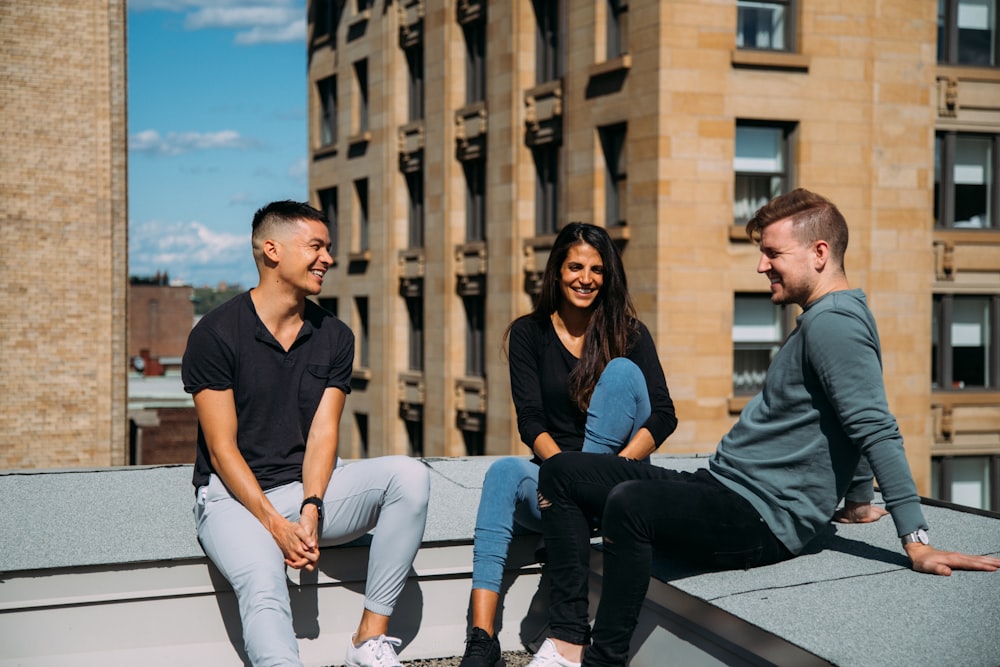 woman sitting between two men in a building rooftop