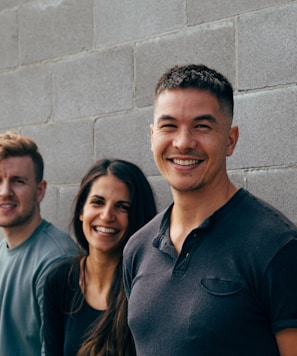 two men and woman smiling leaning on wall