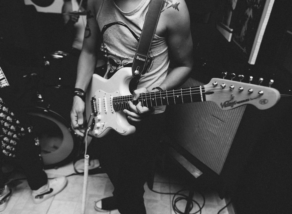 grayscale photography of man playing guitar