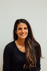 Woman in a black shirt with long hair in front of a wall smiling