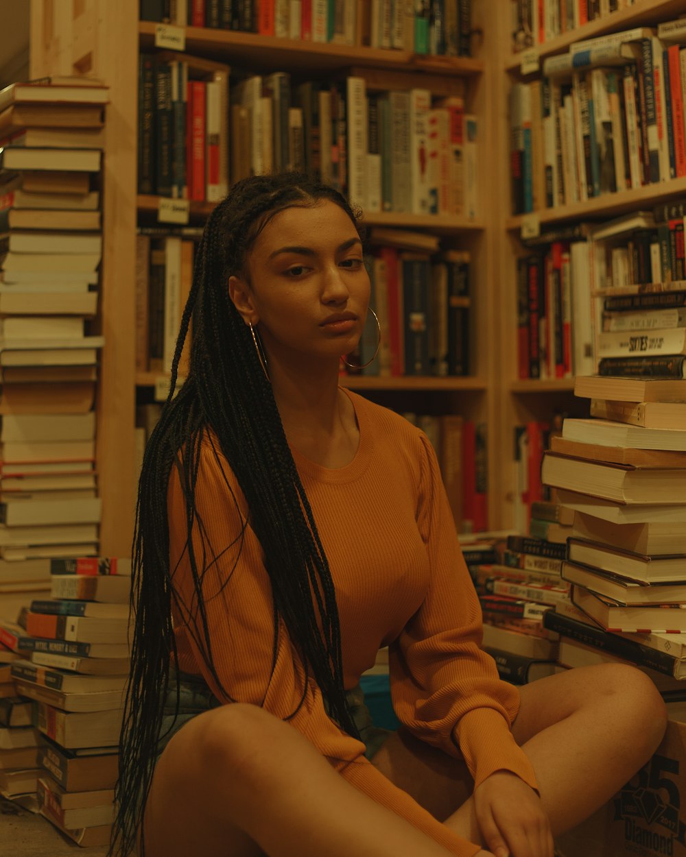 a woman sitting on the floor in front of a bookshelf