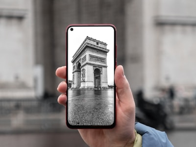 Close-up of a smartphone playing an audio tour with Barcelona landmarks in the background.