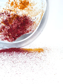 A vibrant plate of colorful Indian spices arranged artistically on a rustic wooden table.