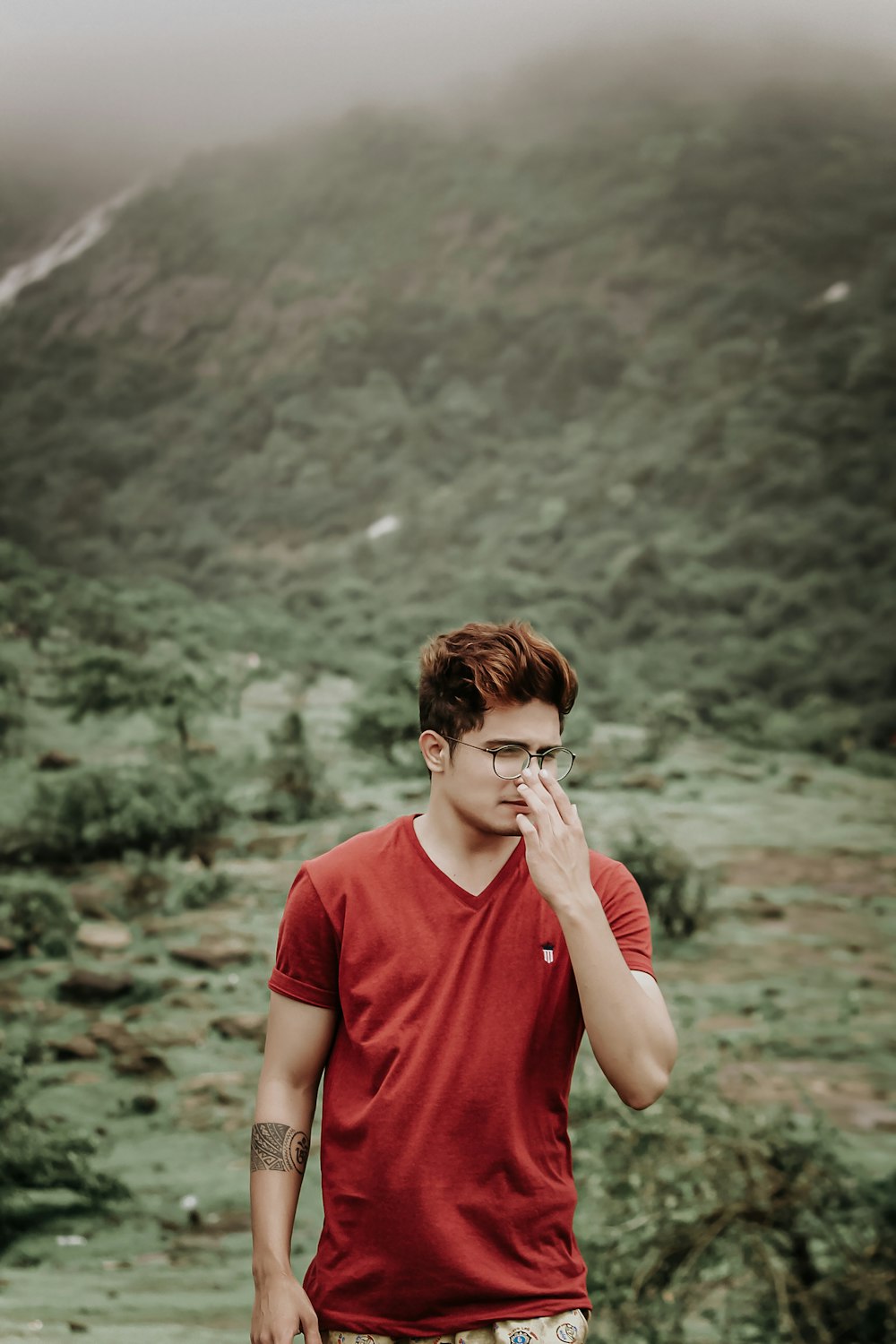 a man in a red shirt standing in front of a mountain