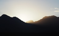 A tranquil landscape with mountains and a sunrise.