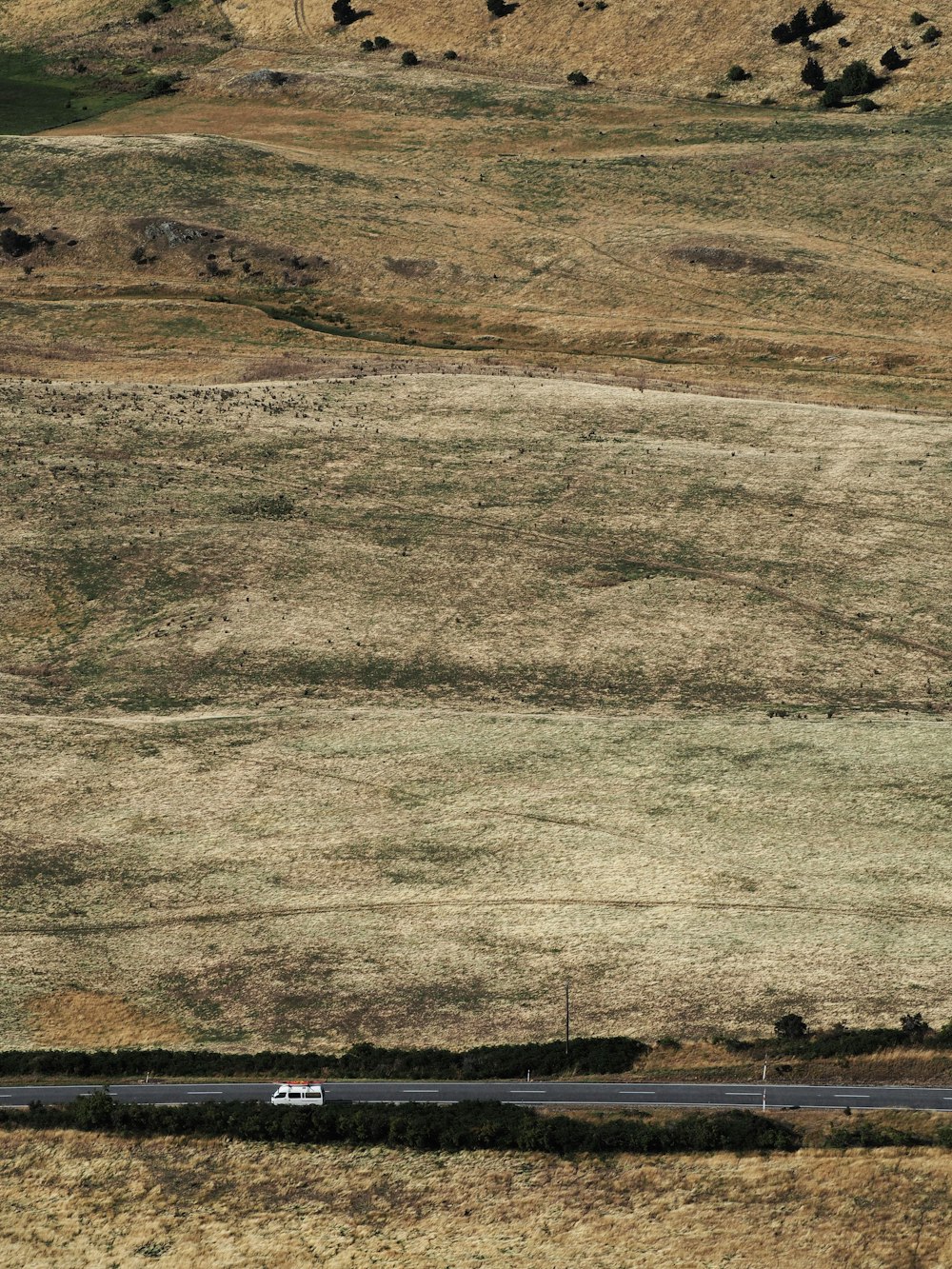 a truck driving down a road in the middle of a field