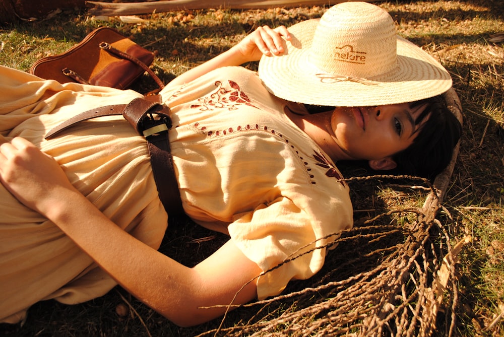 woman lying on grass covering her face with a hat