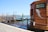 A wooden gondola service booth is situated by a canal with several gondolas moored alongside a wooden dock. The booth bears a sign that reads 'SERVIZIO GONDOLE'. Bright blue sky and water set a serene backdrop, with traditional lampposts lining the dock.
