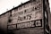 A brick wall displays a large vintage advertisement for Sherwin-Williams Paints and Helena Hardware Co. The painted sign is weathered, showing signs of age and wear, giving it an antique appearance. The text is bold and prominently positioned, with an iconic paint can logo visible on the left.