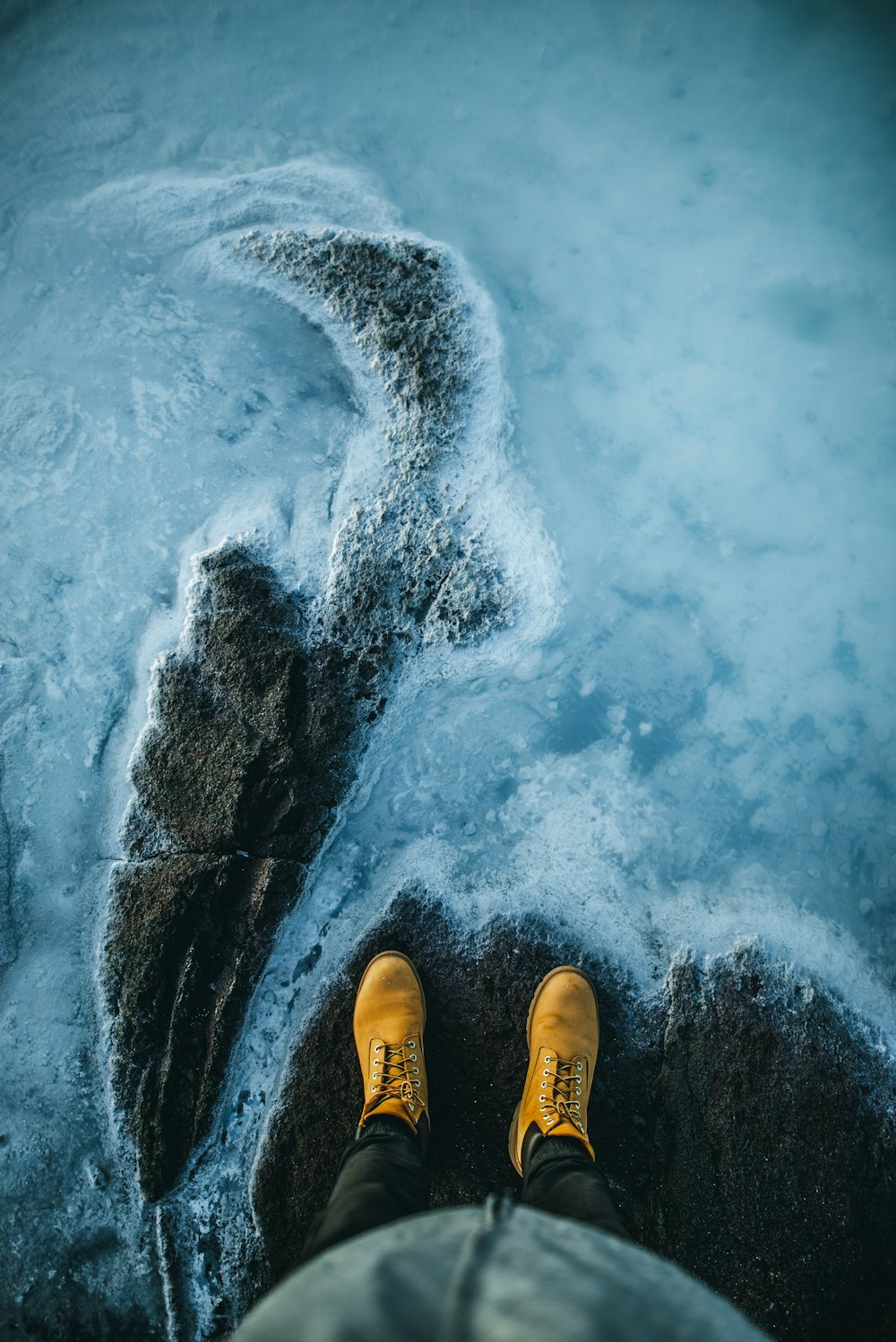 a person wearing yellow shoes standing in the snow
