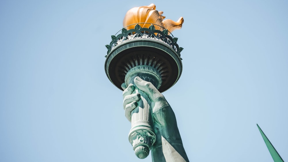 a statue of a hand holding a golden pig on top of a statue of liberty