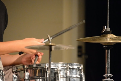 Close-up of a drummer's hands skillfully coordinating sticks over a drum set, highlighting precise technique.