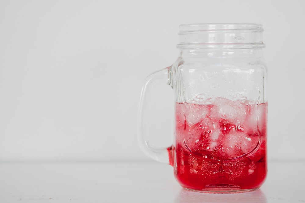 a mason jar filled with red liquid and ice