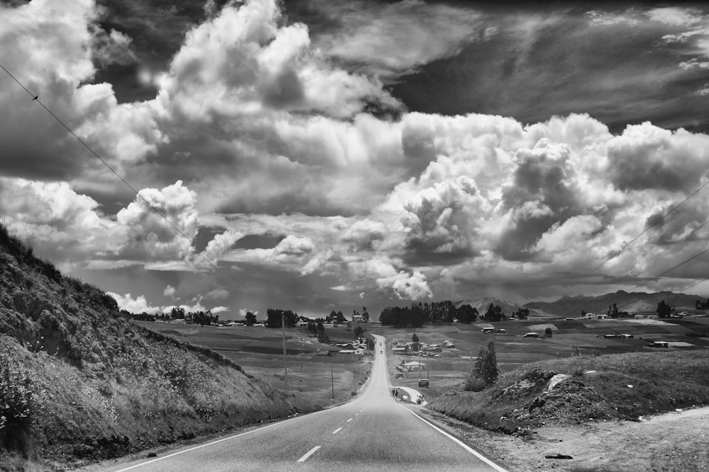 grayscale photo of road near cloudy sky