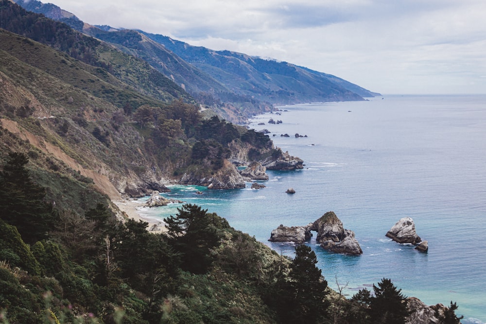 mountain slope by sea during daytime