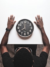 round black and white analog wall clock in front of man