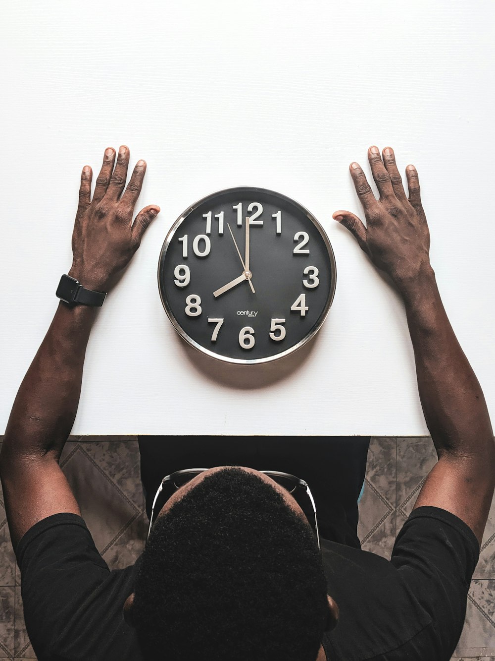 round black and white analog wall clock in front of man