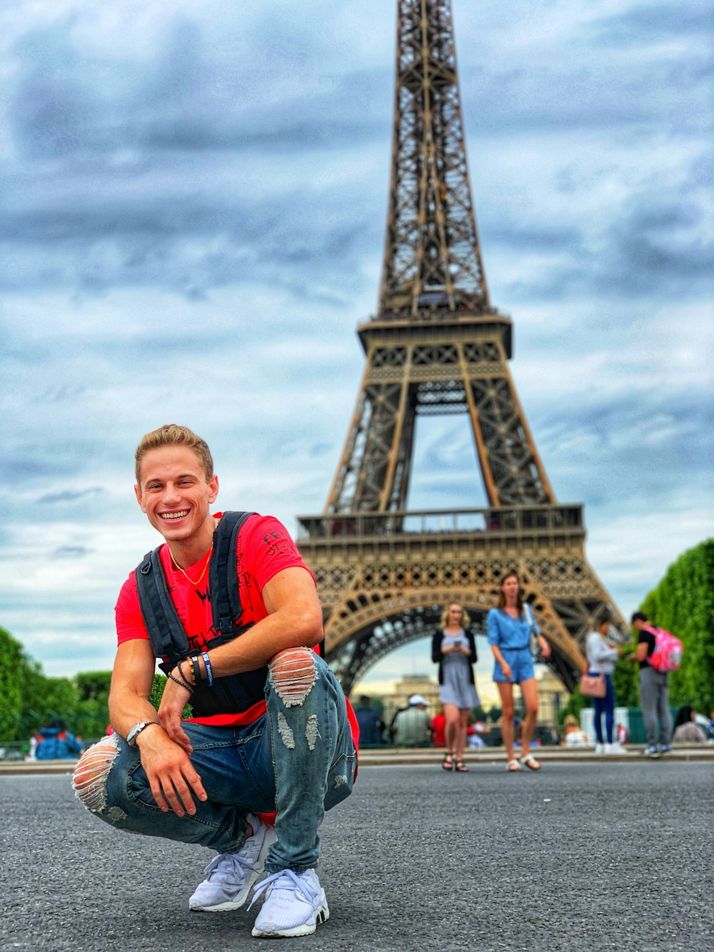 hombre sonriente sentado por un grupo de personas cerca de la torre Eiffel