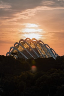 A warm geodesic dome nestled in a lush green landscape under a soft sunset.