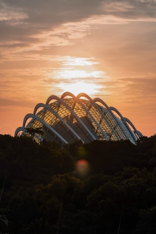 A warm geodesic dome nestled in a lush green landscape under a soft sunset.