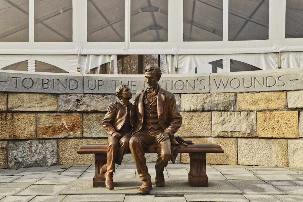 man sitting near boy statue