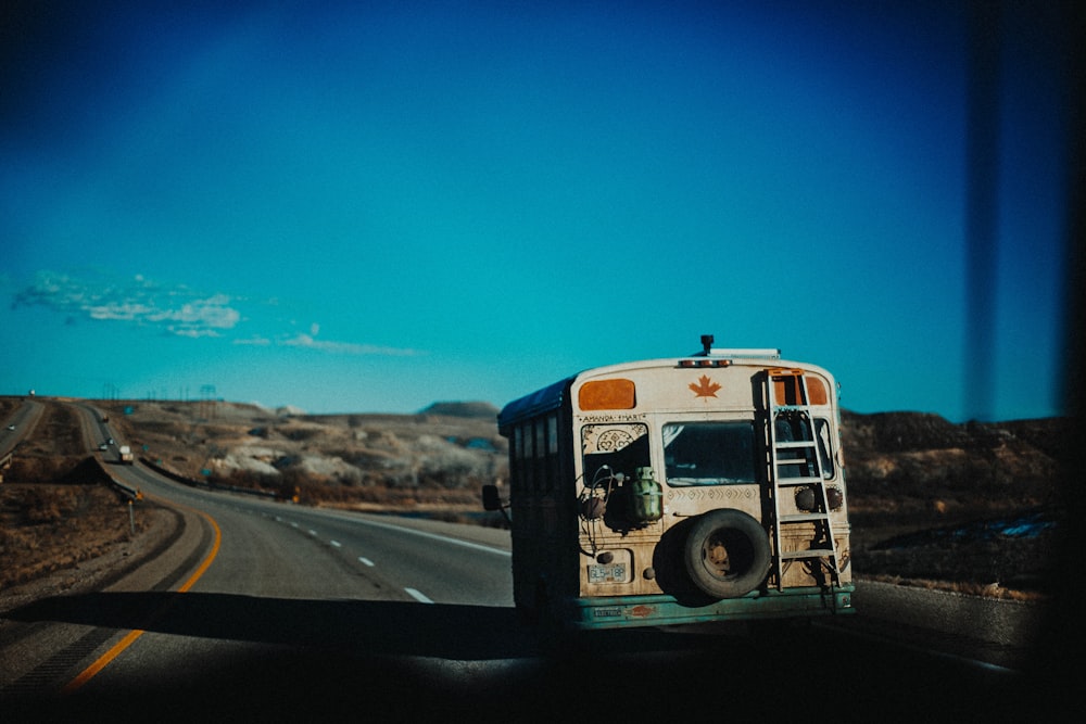 white and brown bus on road under blue and white skies during daytime