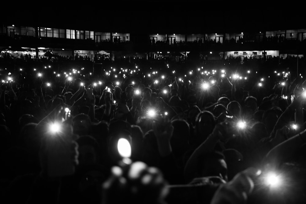 fotografia in scala di grigi di persone vicino all'esterno durante la notte